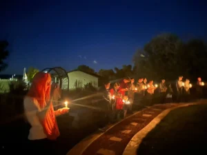 People holding candles during an outdoor nighttime vigil.