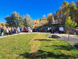 An outdoor religious service near a stone grotto shrine on a sunny day.