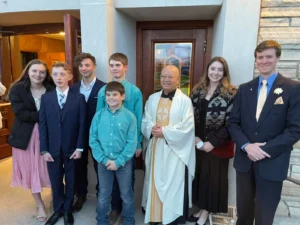 A young child wearing a white gown standing outside next to stone steps.