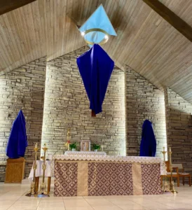 A church sanctuary with statues and a crucifix veiled in purple cloth.